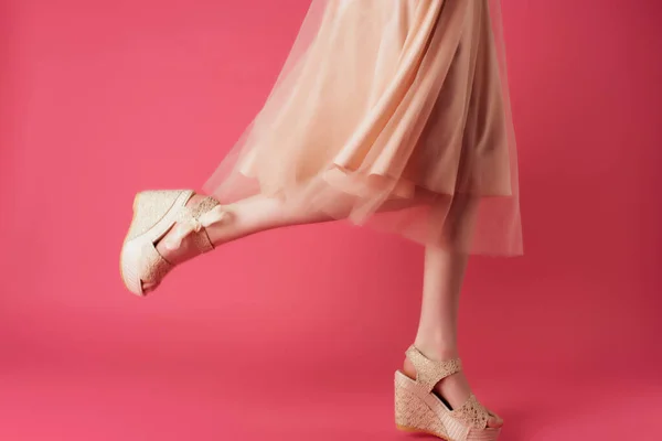 Gambe femminili in scarpe beige posa primo piano sfondo rosa — Foto Stock