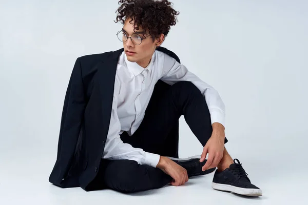 Chico guapo en una chaqueta y camisa y gafas en una habitación luminosa foto estudio modelo peinado pelo rizado —  Fotos de Stock