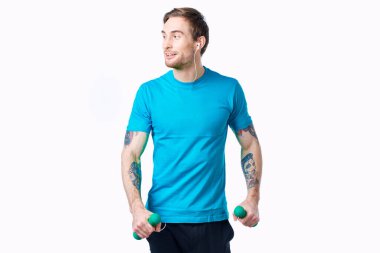 Elinde dambıl tutan yakışıklı sporcu fitness hafif arka plan