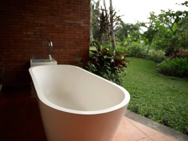 Beyaz banyo arka planda tuğla duvar yeşil çimen egzotik manzara