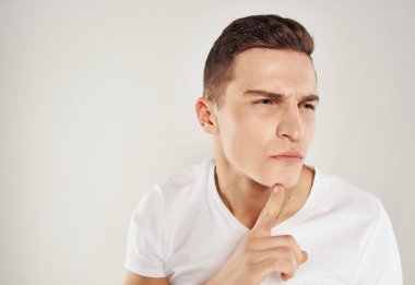 Beyaz tişörtlü, şüpheli görünen, ciddi bir ifadesi olan bir adam.