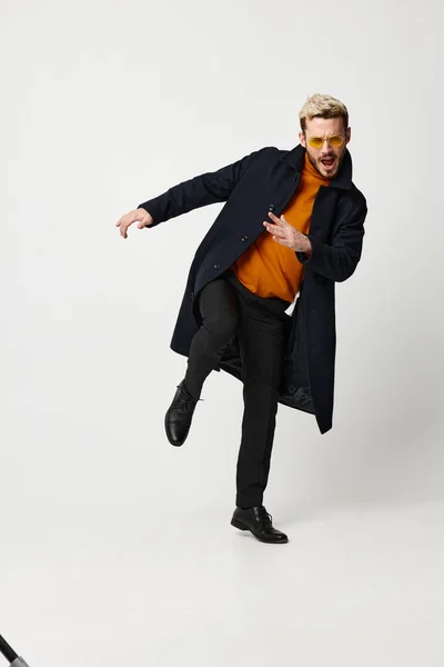 Emocjonalny mężczyzna w pomarańczowy sweter czarny kurtka lekki tło buty model — Zdjęcie stockowe