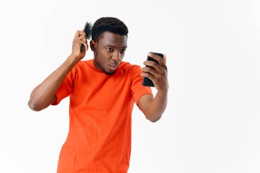 Ellerinde tarak olan bir adam, saçının bakımına bakar.