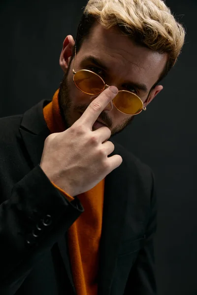 Elegantes hombres enderezar gafas en la cara y suéter naranja modelo chaqueta negra —  Fotos de Stock