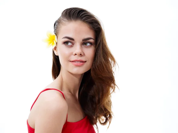 Brunett kvinna med en gul blomma i håret på en ljus bakgrund beskärd utsikt leende — Stockfoto