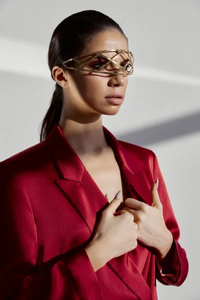 Glamoureuze vrouw met sieraden en in een rood jasje gebaren met haar handen op een lichte achtergrond — Stockfoto