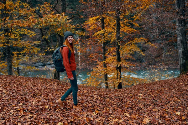 Een reiziger met een rugzak wandelingen in het park in de natuur in de buurt van de rivier in de herfst — Stockfoto