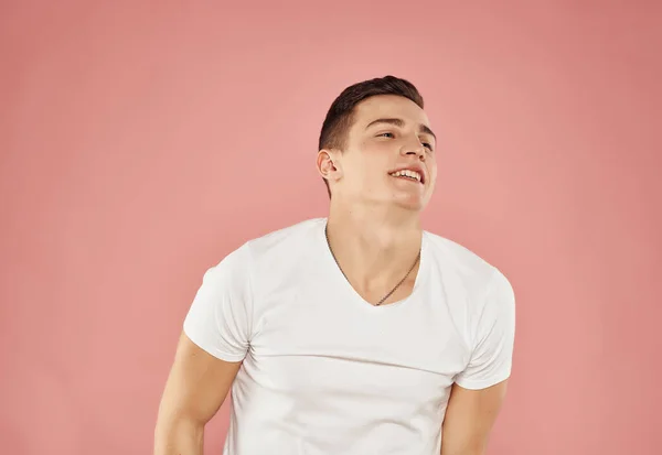 Homem alegre em uma camiseta branca gesticulando com as mãos fundo rosa — Fotografia de Stock