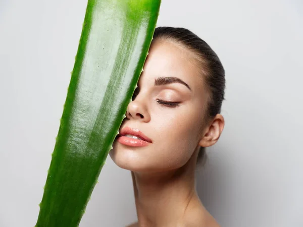 Mulher segurando folha de aloés na frente de seu rosto e olhos fechados pele limpa cosmetologia dermatologia — Fotografia de Stock