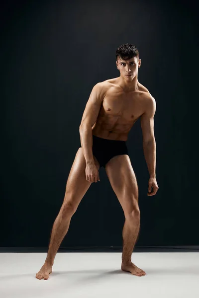 Man in black shorts with a pumped body on a dark background model — Stock Photo, Image