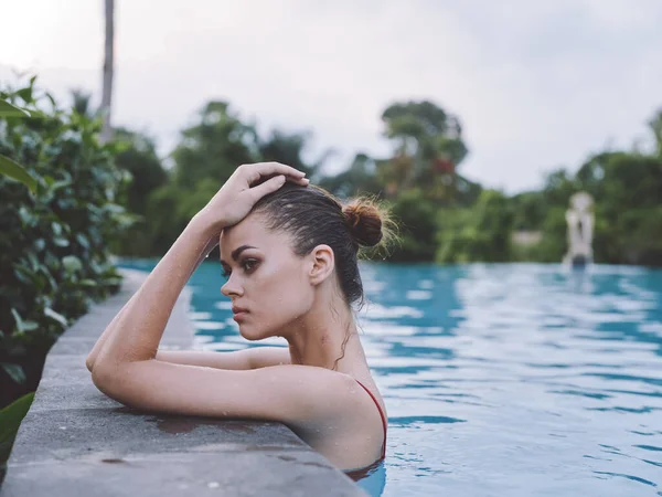 Sexy vrouw in badpak leunen op zwembad tegel en zijaanzicht — Stockfoto