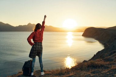 Yükselmiş el manzaralı kadın turist gün batımı tatili