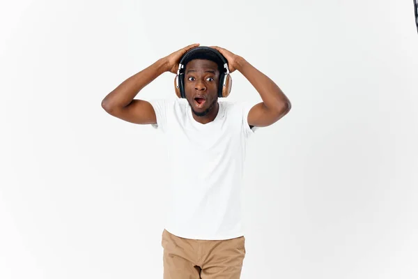 Sorprendido hombre en auriculares música gestos con las manos emociones fondo claro — Foto de Stock