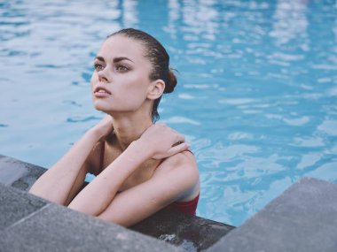 Mayolu seksi kadın havuzda yüzüyor ve dirsekleriyle fayansa yaslanıyor.