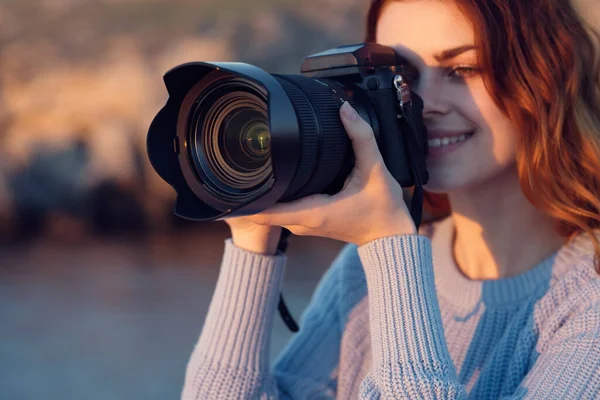 Όμορφη κοκκινομάλλα γυναίκα με μια φωτογραφική μηχανή στη φύση στα βουνά κοντά στο ποτάμι — Φωτογραφία Αρχείου