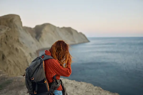 Рудий мандрівник з рюкзаком на спині дивиться на море і гори на відстані — стокове фото