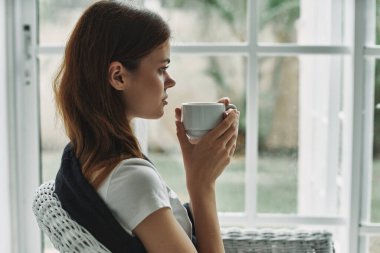 woman at home near the window with a cup of coffee rest
