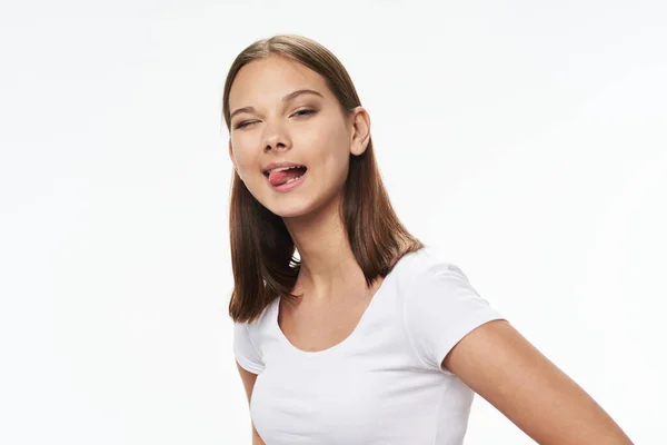 Pretty woman in a white t-shirt grimaces on a light background — Φωτογραφία Αρχείου