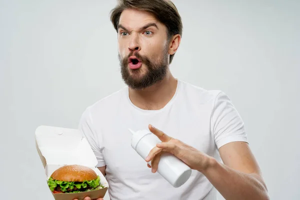 Man met hamburger gebaar met zijn handen en verrast kijken open mond model — Stockfoto