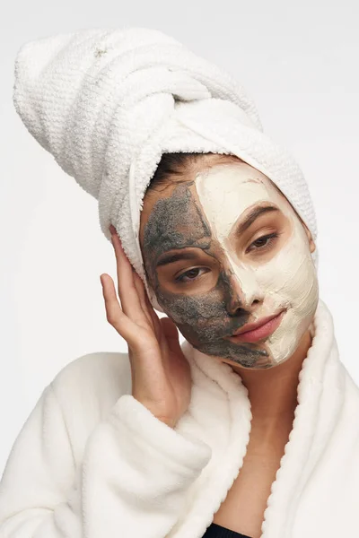 Woman with a mask on her face against black dots skin care and a towel on her head — Stok Foto