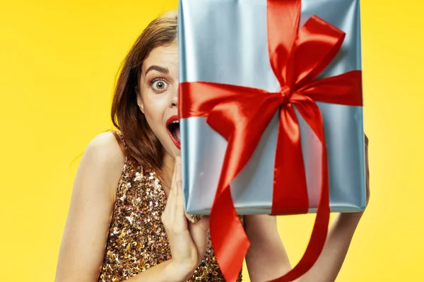 Frau hält ein Geschenk Urlaub Weihnachtsdekoration gelb Hintergrund — Stockfoto