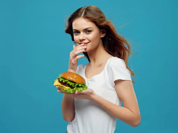 Mujer delgada con hamburguesa Warface sobre fondo azul vista recortada — Foto de Stock