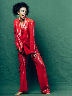 woman in a red suit on a green background in full growth curly hair model