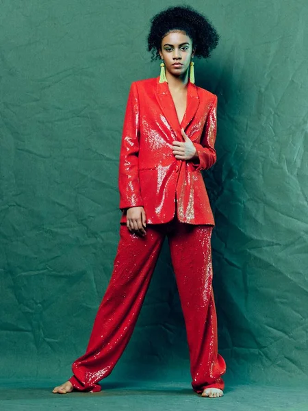 Vrouw in rood pak decoratie glamour mode groene achtergrond — Stockfoto