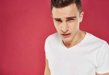 Beyaz tişörtlü adam kırmızı arka plan stüdyo duygularını kırptı.