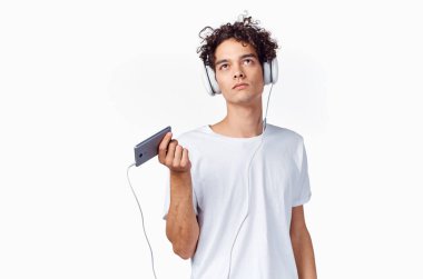 Kulaklıklı, elinde telefon olan kıvırcık saçlı adam. Müzik teknolojisi.
