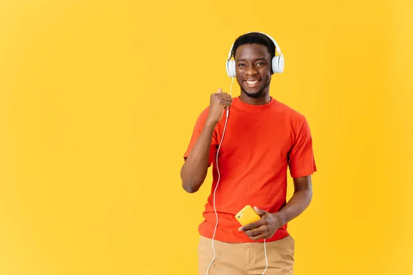 Uomo sorridente con tecnologia cuffie musica sfondo giallo — Foto Stock