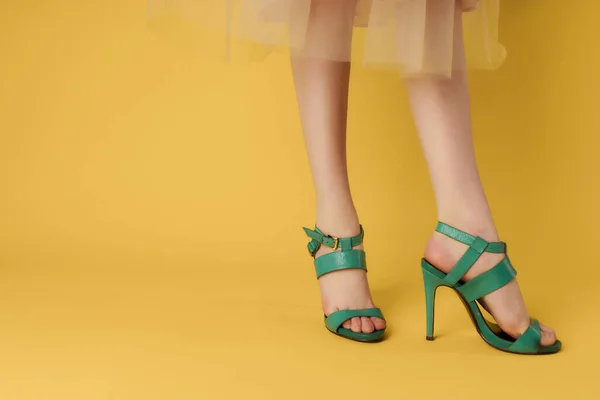 Gambe femminili phasing verde scarpe estate stile giallo sfondo — Foto Stock