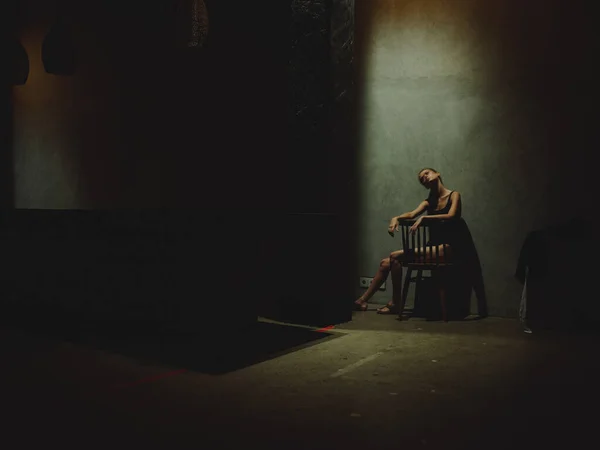 Femme seule assise sur une chaise dans une pièce sombre dépression conflit stress modèle émotions — Photo