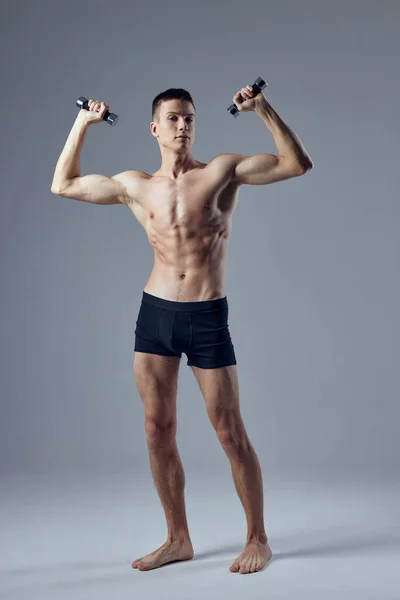 Bodybuilder avec haltères dans les mains pompé exercice d'entraînement du corps fond isolé — Photo