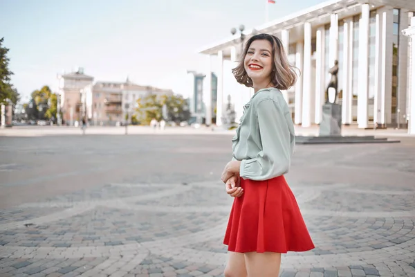 Fröhliche Frau im roten Rock auf dem Platz beim Stadtbummel — Stockfoto