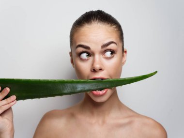 Kadın aloe yaprağını kemiriyor çıplak omuzlar makyaj portresi. 