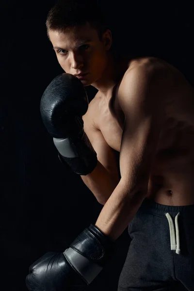 Boxer se naklonil dopředu na černém pozadí s rukavicemi — Stock fotografie