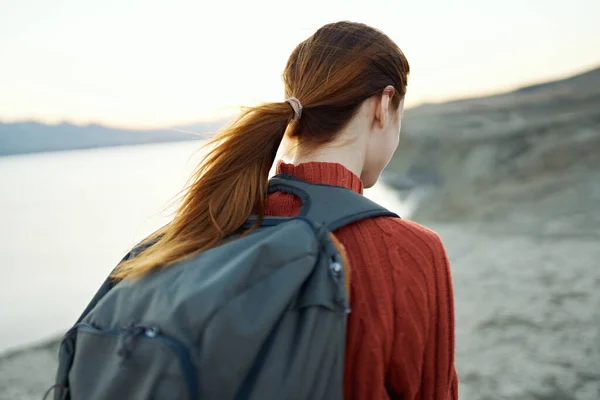 Donna dai capelli rossi con uno zaino sulla schiena passeggiate nella natura in montagna con uno zaino sulla schiena — Foto Stock