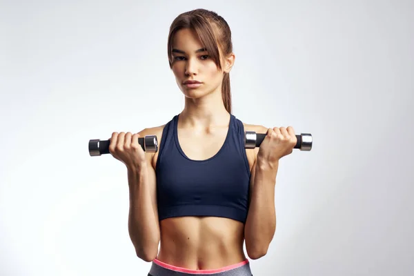 Pretty athletic woman with dumbbells in hands pumping up muscles fitness — Stock Photo, Image