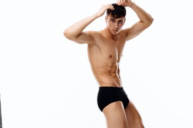 Açık arkaplanda poz veren siyah şortlu bir sporcu. Elleri başındaki manzarayı tutuyor.