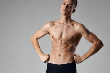 Gövdesi şişmiş seksi vücut geliştirici gri arka planda el ele tutuşuyor.