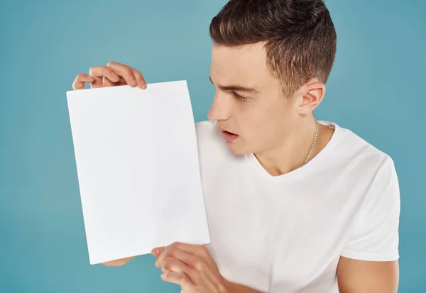 Knappe man in een wit t-shirt een vel papier in zijn handen Kopieer Space close-up — Stockfoto