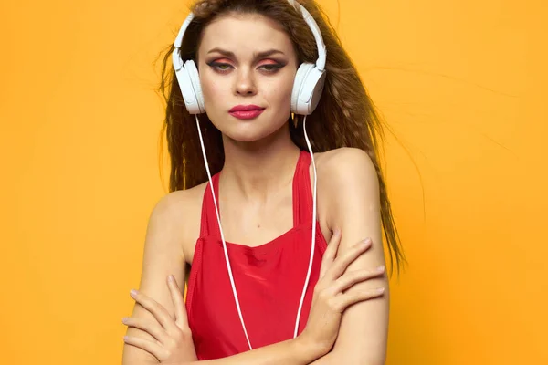 Mulher bonita em t-shirt vermelha usando fones de ouvido tecnologia música fundo amarelo — Fotografia de Stock