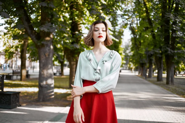 Pretty woman in red skirt in the park walk lifestyle fresh air — Stock Photo, Image