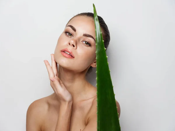 Bonita mujer joven sosteniendo hoja de aloe verde en la mano —  Fotos de Stock