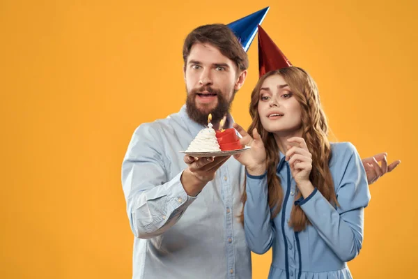 Engraçado homem e mulher bolo com vela feriado divertido fundo amarelo — Fotografia de Stock