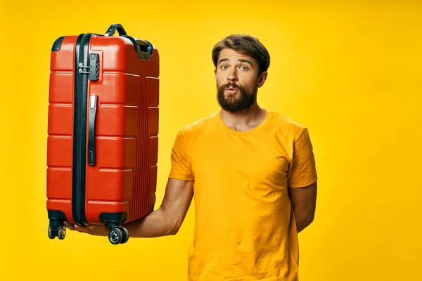 Muž s červeným kufrem dovolená cestování cestující žluté pozadí — Stock fotografie