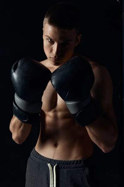 Pugile in guanti neri su uno sfondo scuro gonfiato busto bodybuilder fitness — Foto Stock