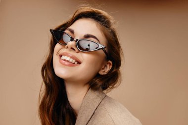 Güneş gözlüklü mutlu kadının portresi gülüşü bej arka plan kırpılmış görünüm