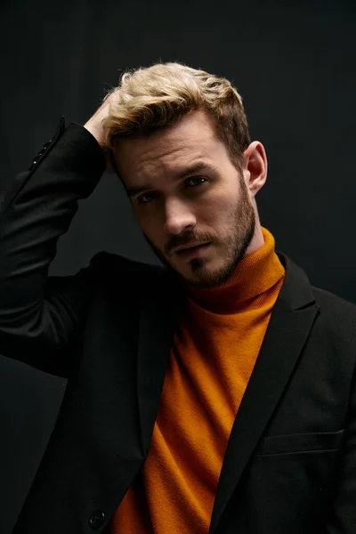 Portrait of handsome blond man in jacket orange sweater on dark background close-up cropped view — Stock Photo, Image